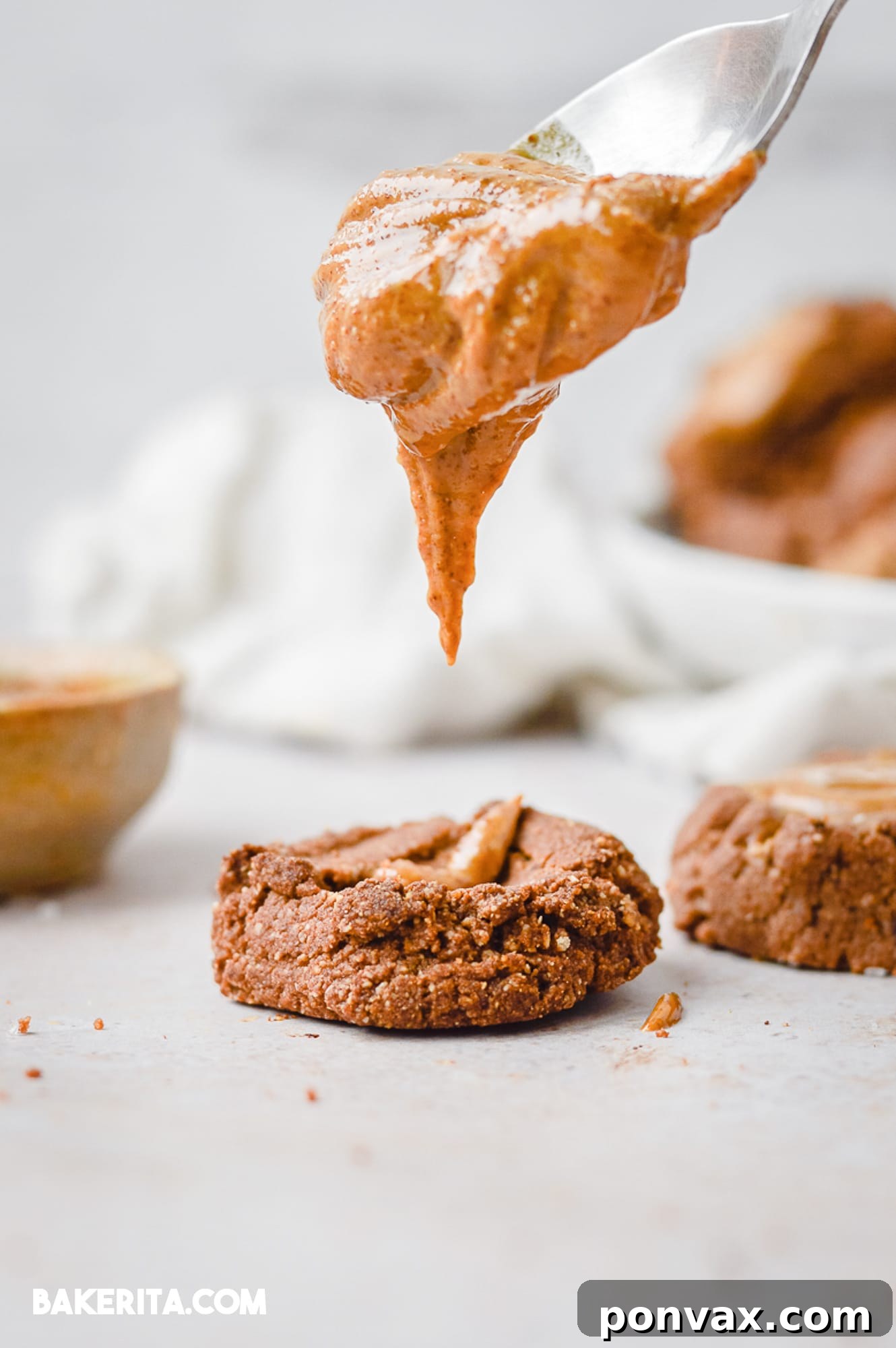 A hand pressing a thumbprint into chocolate cookie dough balls on a baking sheet.