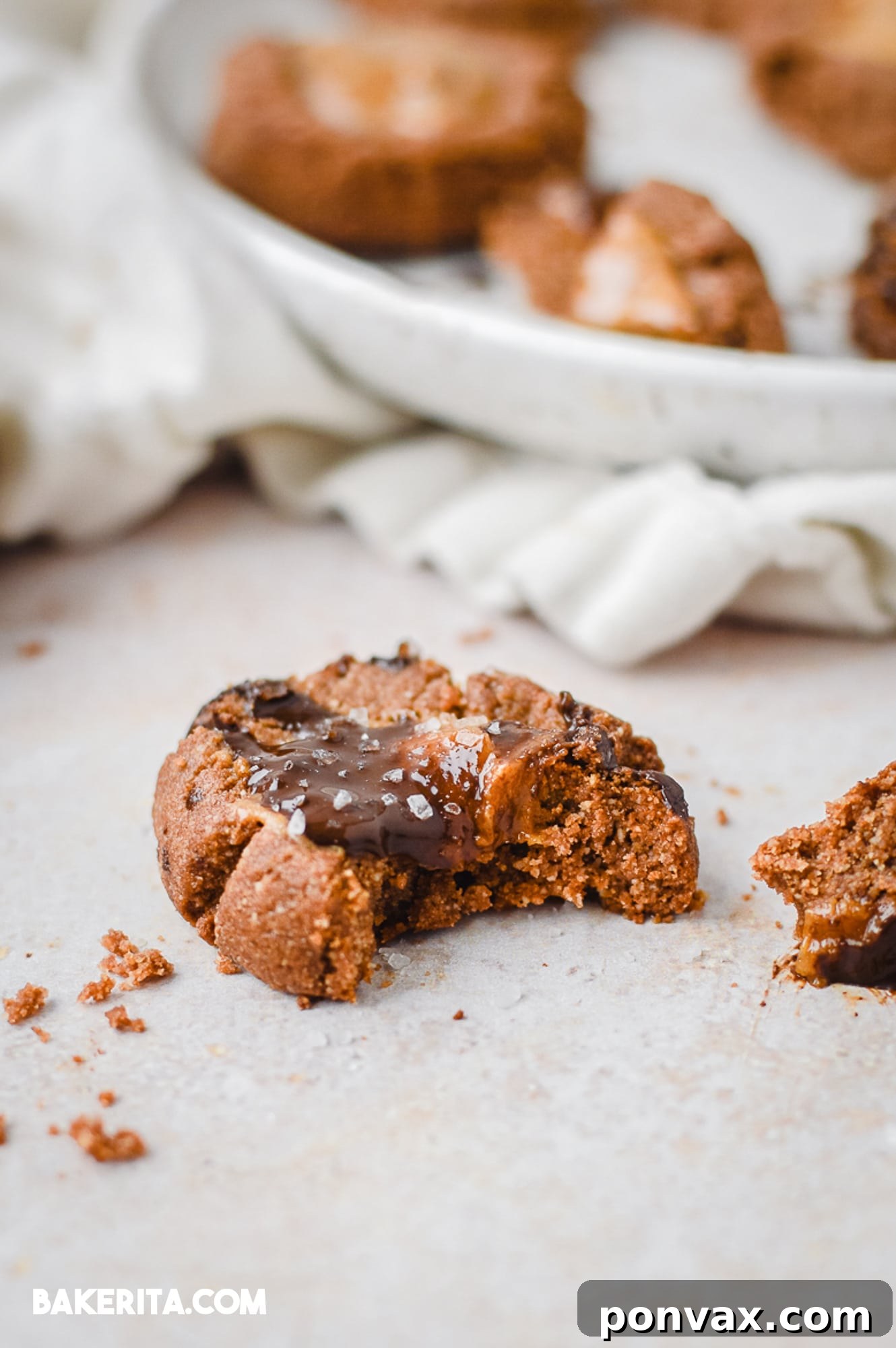 A close-up of a stack of chocolate almond butter thumbprint cookies, showing the rich filling.