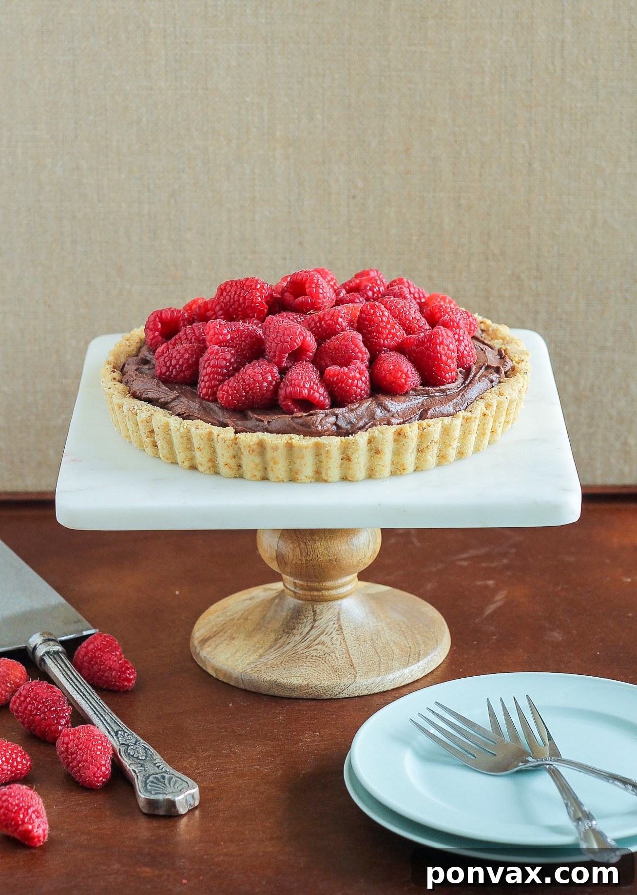 A beautifully styled Whipped Chocolate Ganache Raspberry Tart, showcasing its rich chocolate filling and fresh berry topping on an almond flour crust.