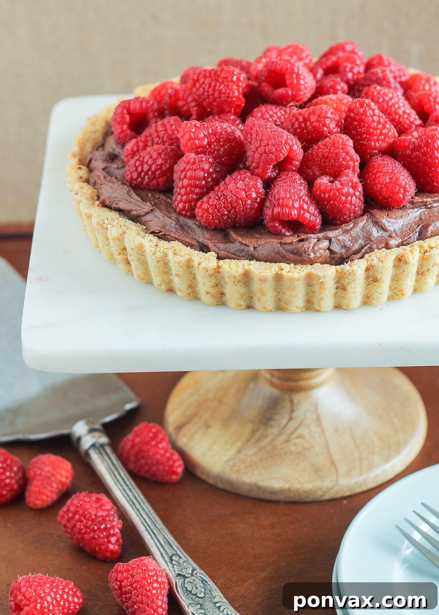 A close-up of the partially assembled Chocolate Ganache Raspberry Tart, showing the dark chocolate ganache filling in the almond flour crust before topping with berries.
