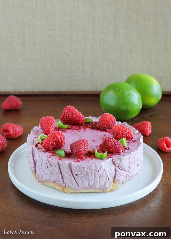 Creamy Vegan Raspberry Lime Cheesecake with Coconut Crust, decorated with fresh raspberries and lime zest.