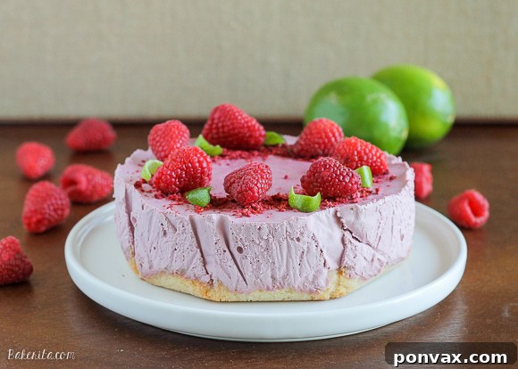 Finished Vegan Raspberry Lime Cheesecake garnished with fresh raspberries, coconut, and edible flowers.