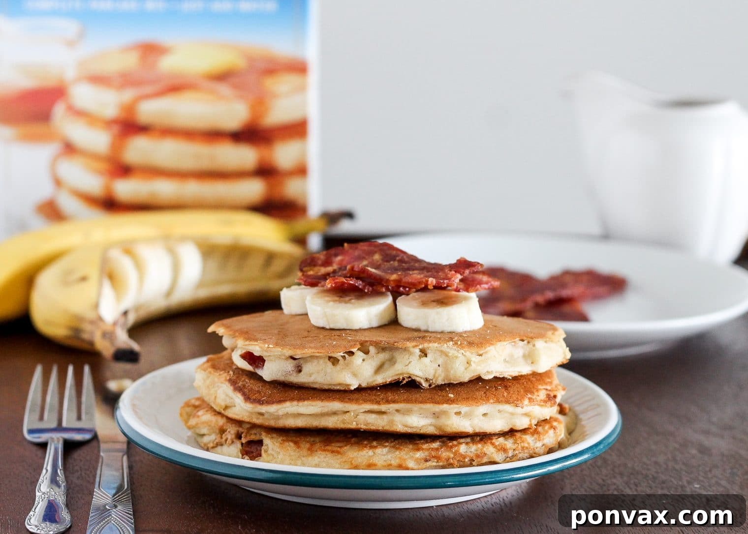 Close-up of fluffy Elvis Pancakes, showcasing the rich banana peanut butter batter and hints of the bacon and peanut butter filling.