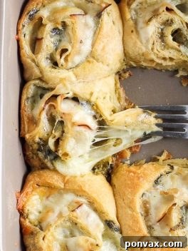 Cheesy Turkey Pesto Pinwheels 7 A close-up overhead shot of a single Cheesy Turkey Pesto Roll, revealing the spiral of ingredients and perfectly baked crescent dough.